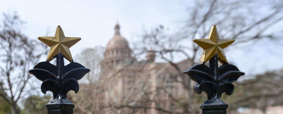 背景为德克萨斯州国会大厦，前景为国会大厦围墙上的铜星